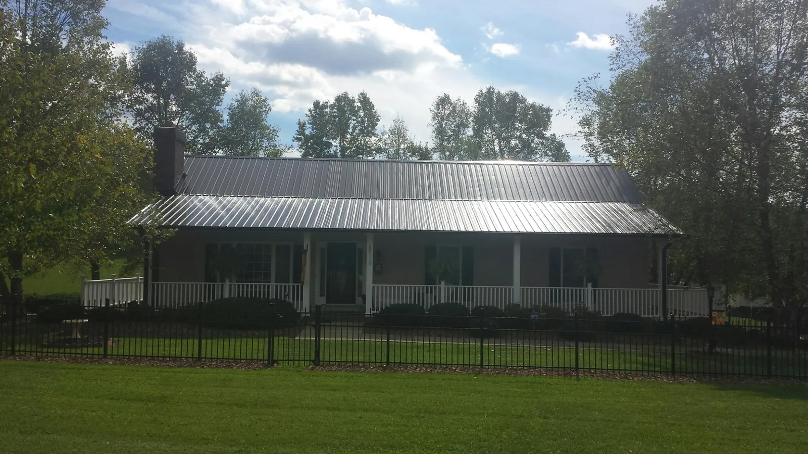 Gray metal roof on a brick ranch with a full width front porch — Gutter Guard Installation work by our crew in Youngwood