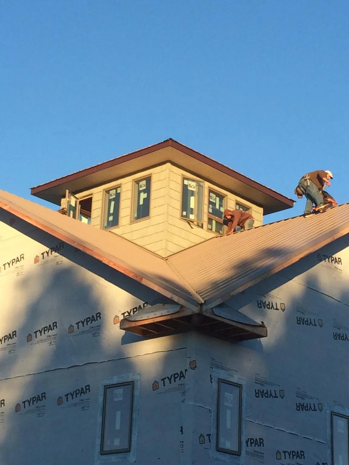 Roofers working around a rooftop cupola on a new metal roof at sunset — Roof Waterproofing in Youngwood by Roofing Brothers